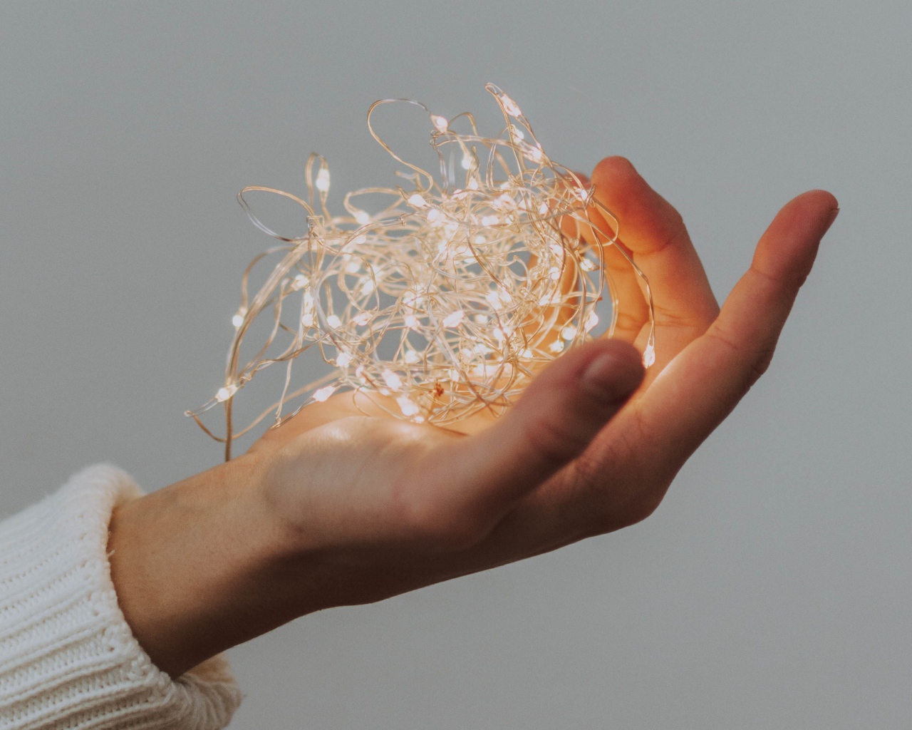 Включенная гирлянда в руке на сером фоне