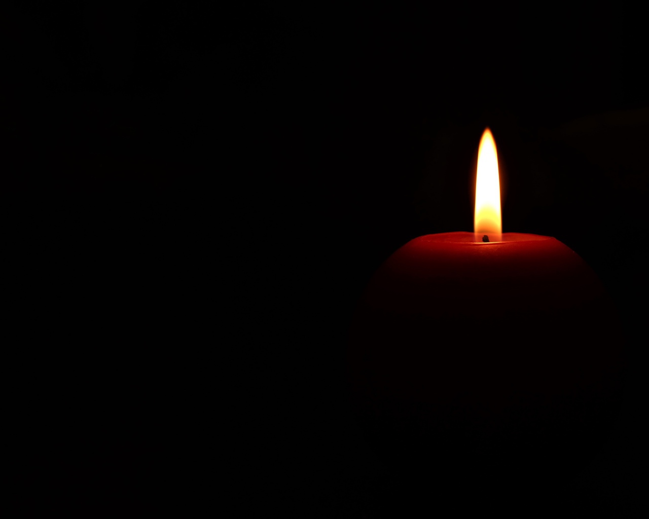 Зажженная красная свеча на черном фоне