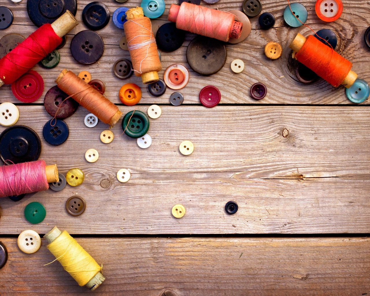 Разноцветные пуговицы и нитки лежат на столе