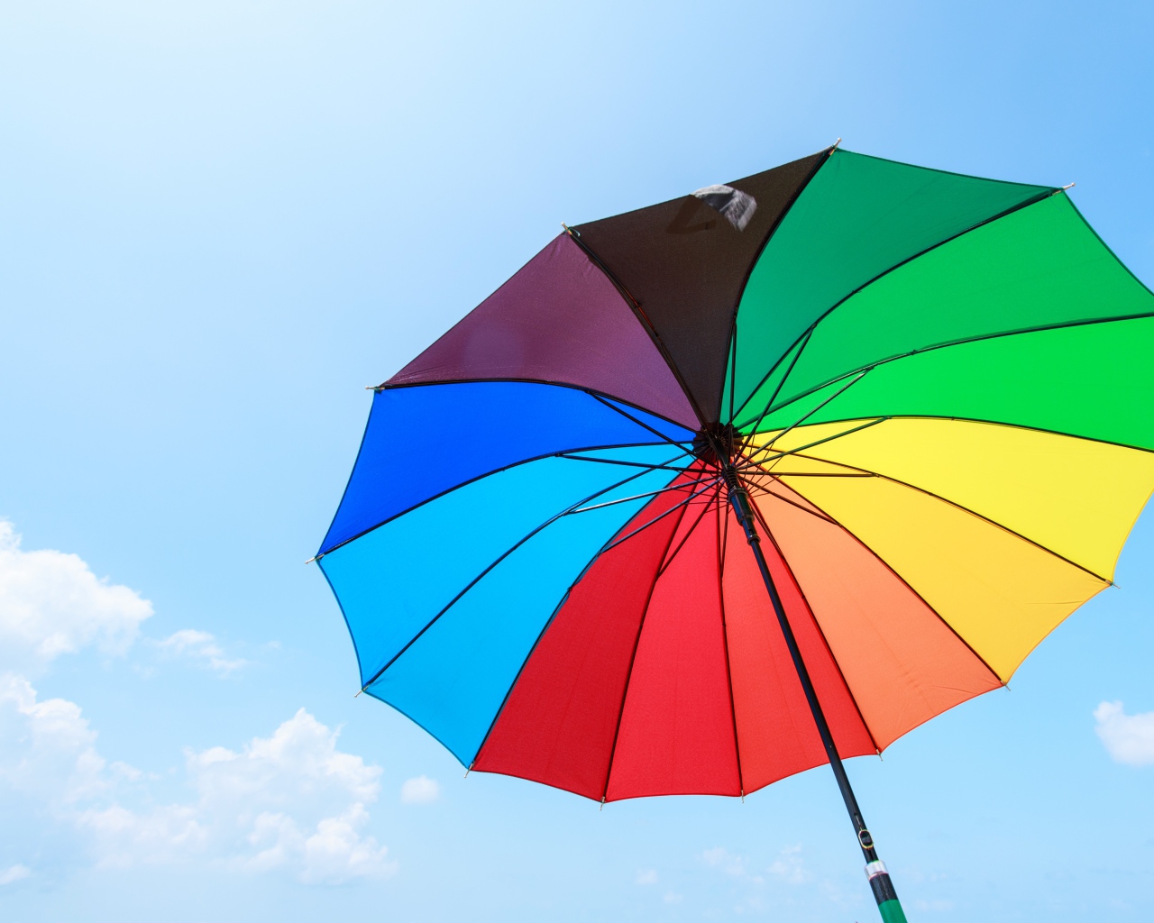 Разноцветный зонт на фоне голубого неба 