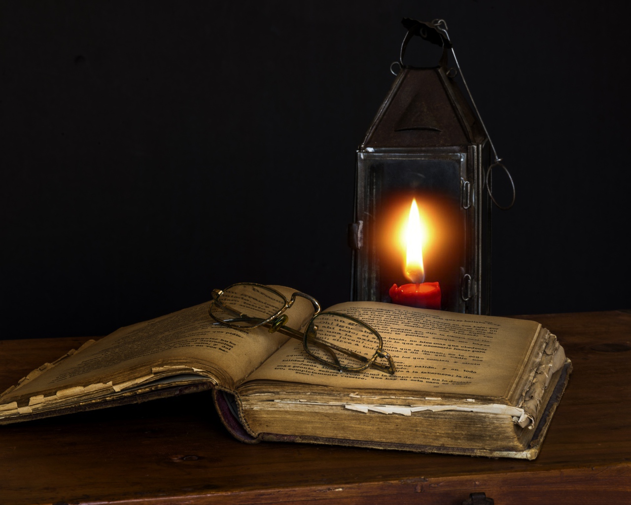 Старая книга на столе с очками и лампой