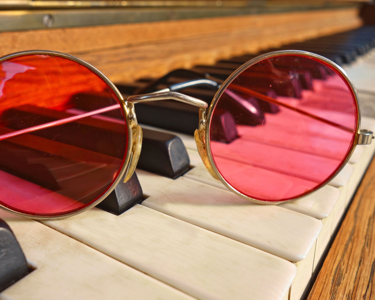 Розовые очки лежат на клавишах рояля