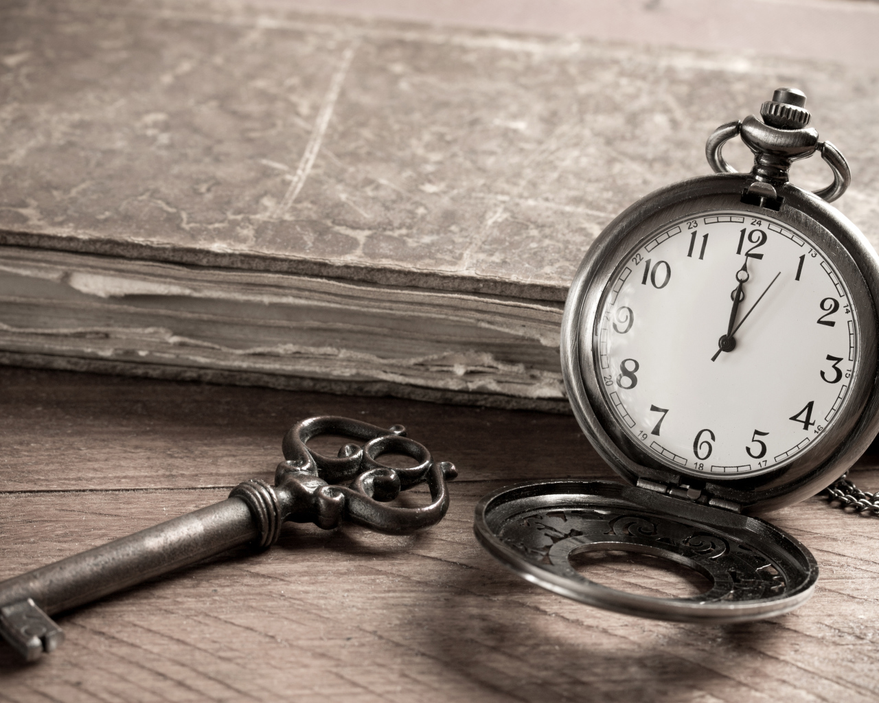 Карманные часы на столе с ключом и старой книгой 