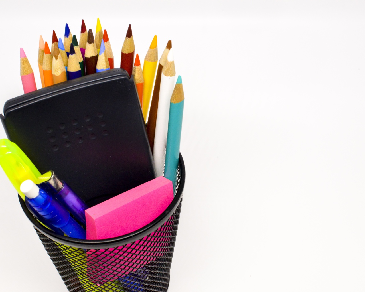 Канцелярские предметы в черном стакане на белом фоне 