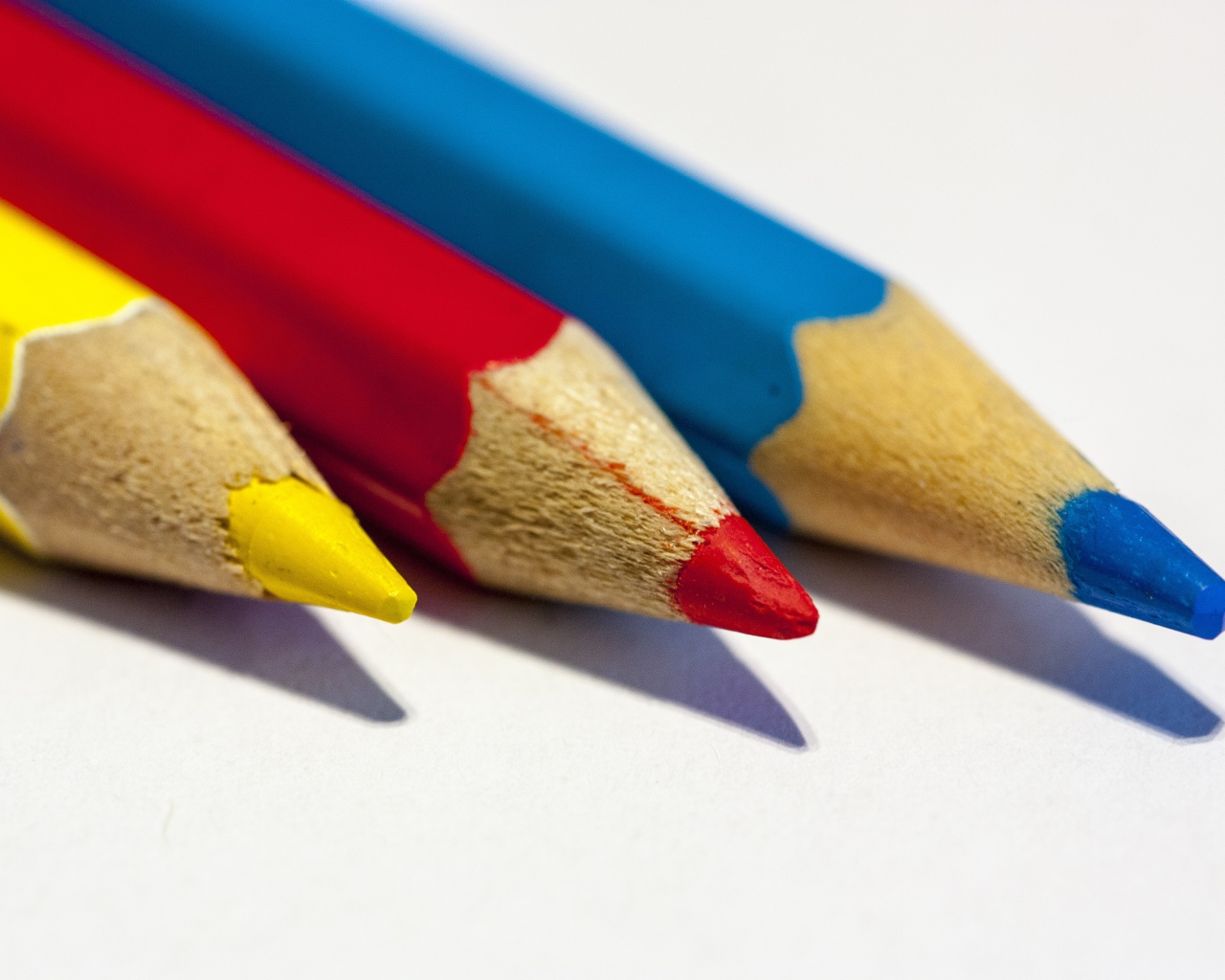 Три разноцветных карандаша на белом фоне