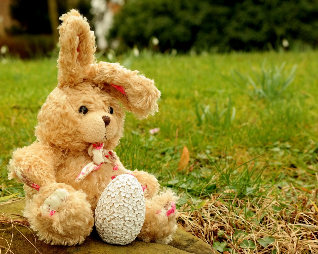 Игрушка заяц на камне в траве