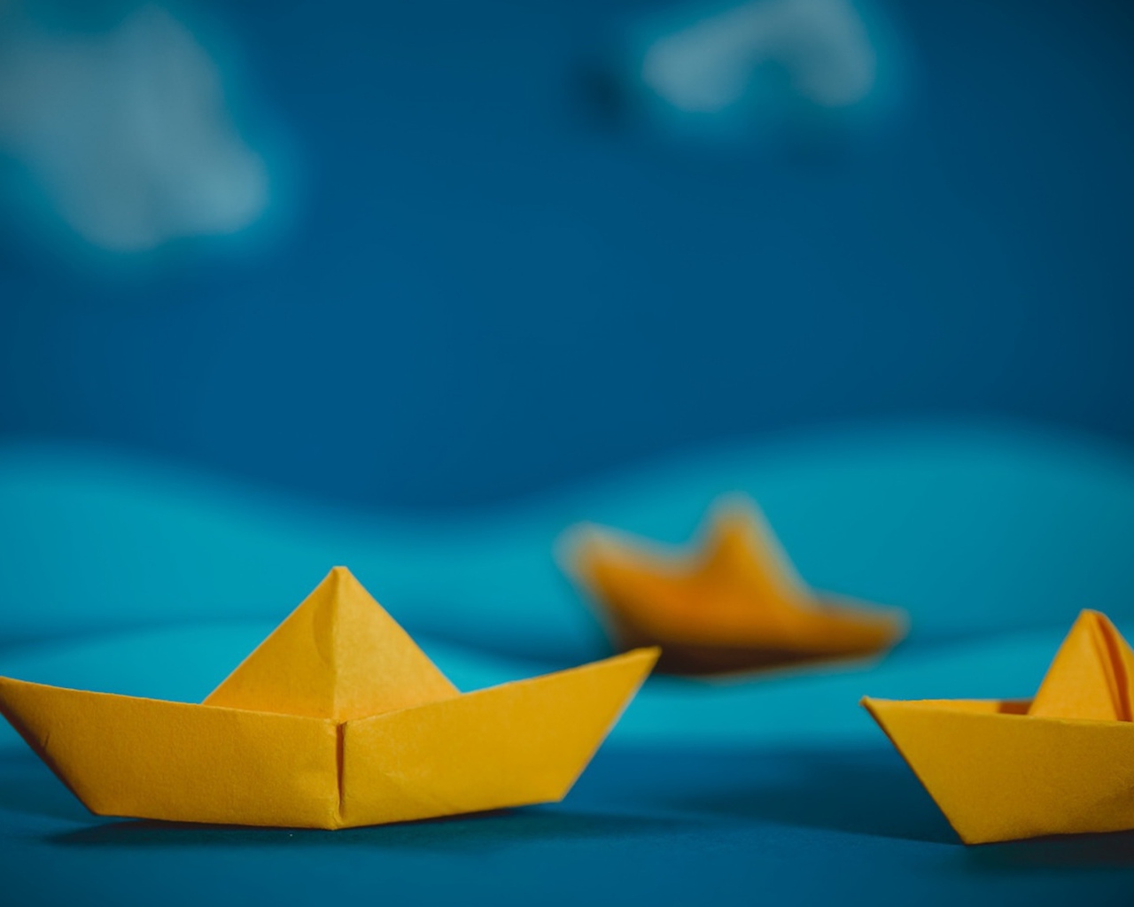 Желтые кораблики оригами на синем фоне