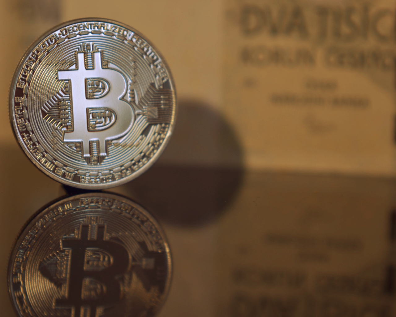 Монета биткоин отражается в зеркальной поверхности 