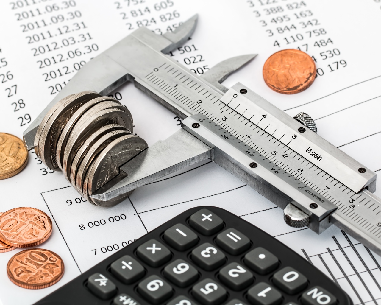 Монеты на столе с штангенциркулем и калькулятором