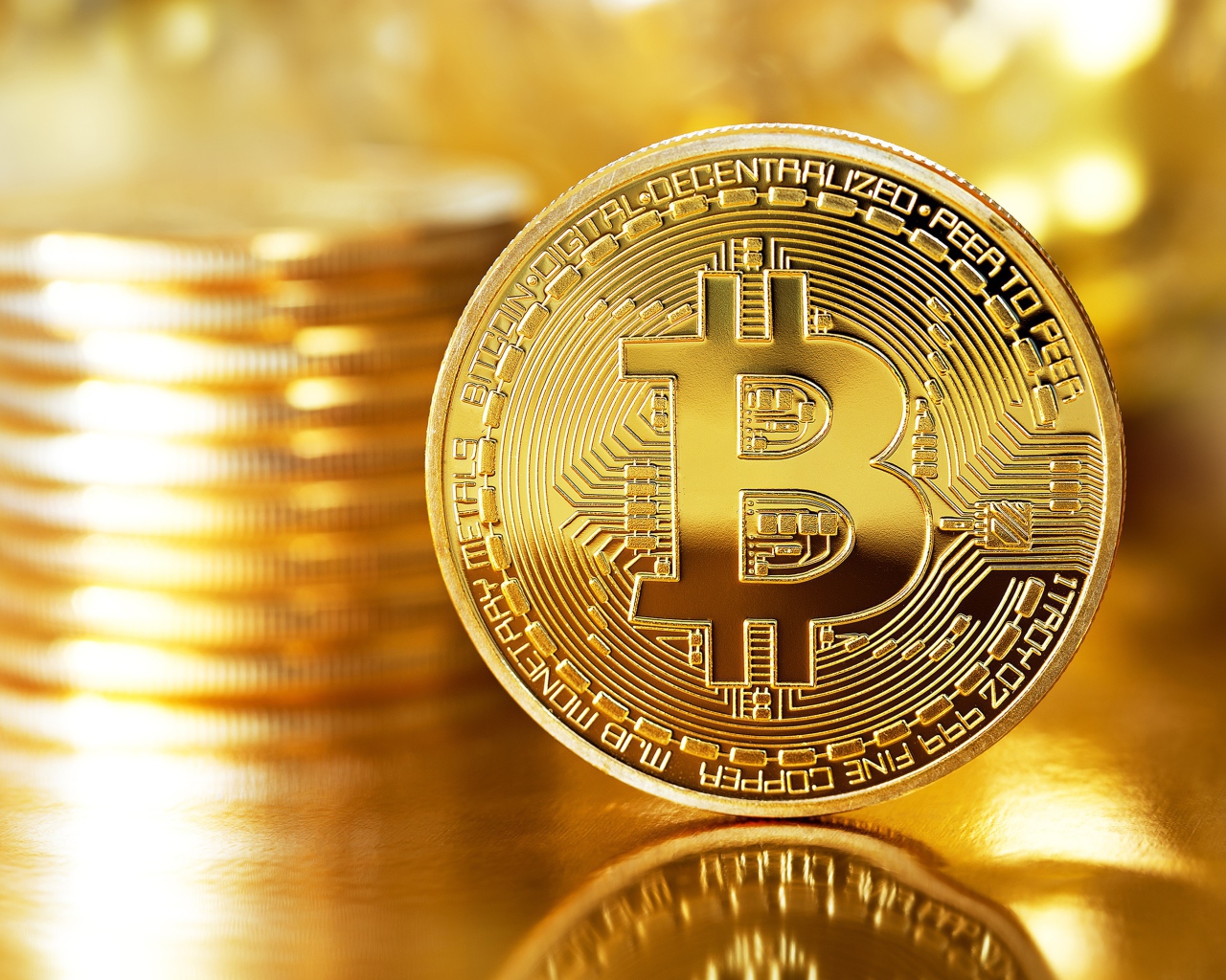 Золотая монета биткоин отражается в поверхности стола 