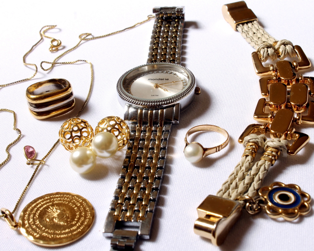 Наручные часы и золотые украшения на белом фоне