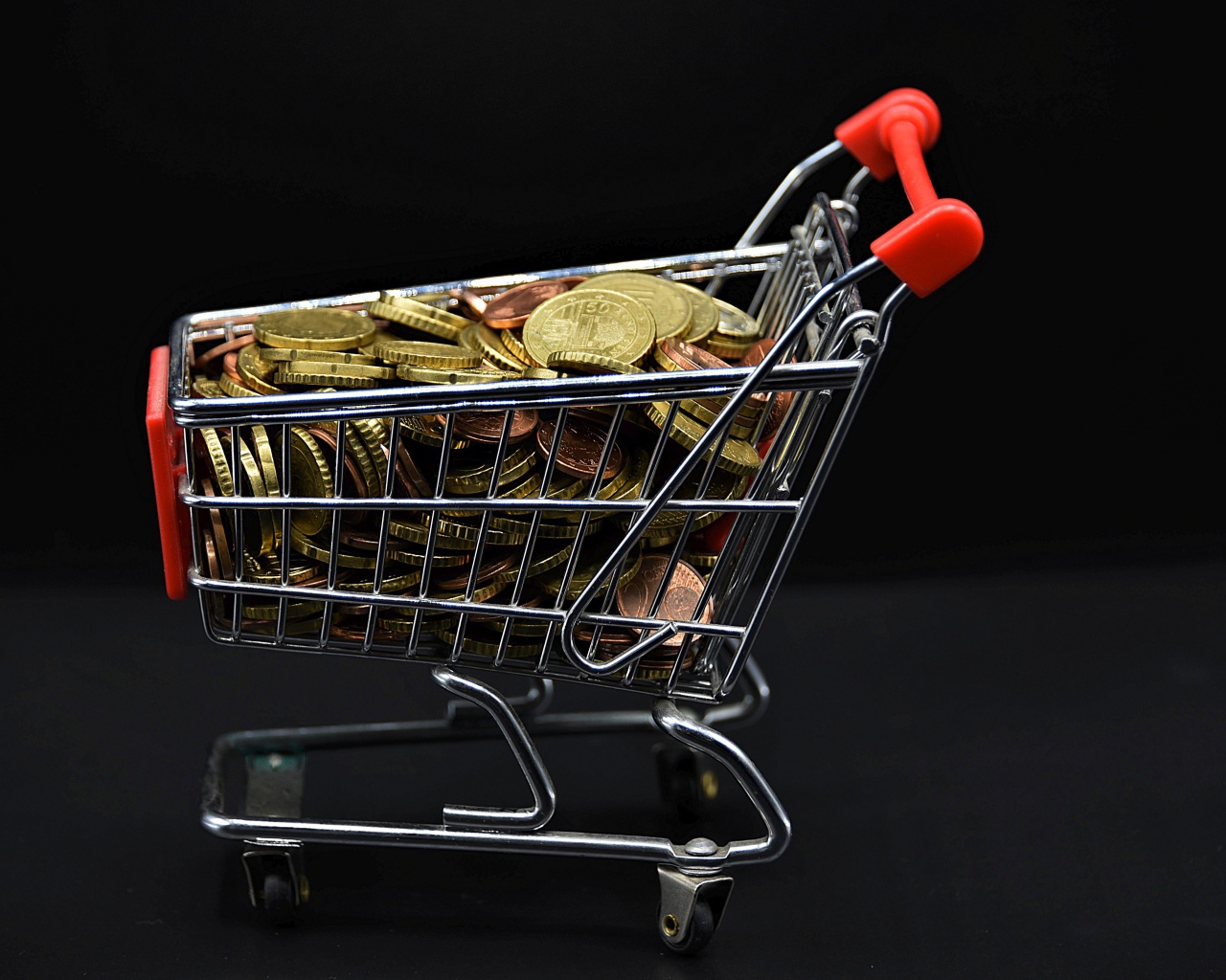 Железная тележка с монетами на черном фоне 