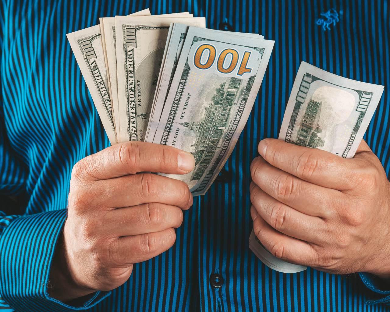 Мужчина считает сто долларовые купюры 