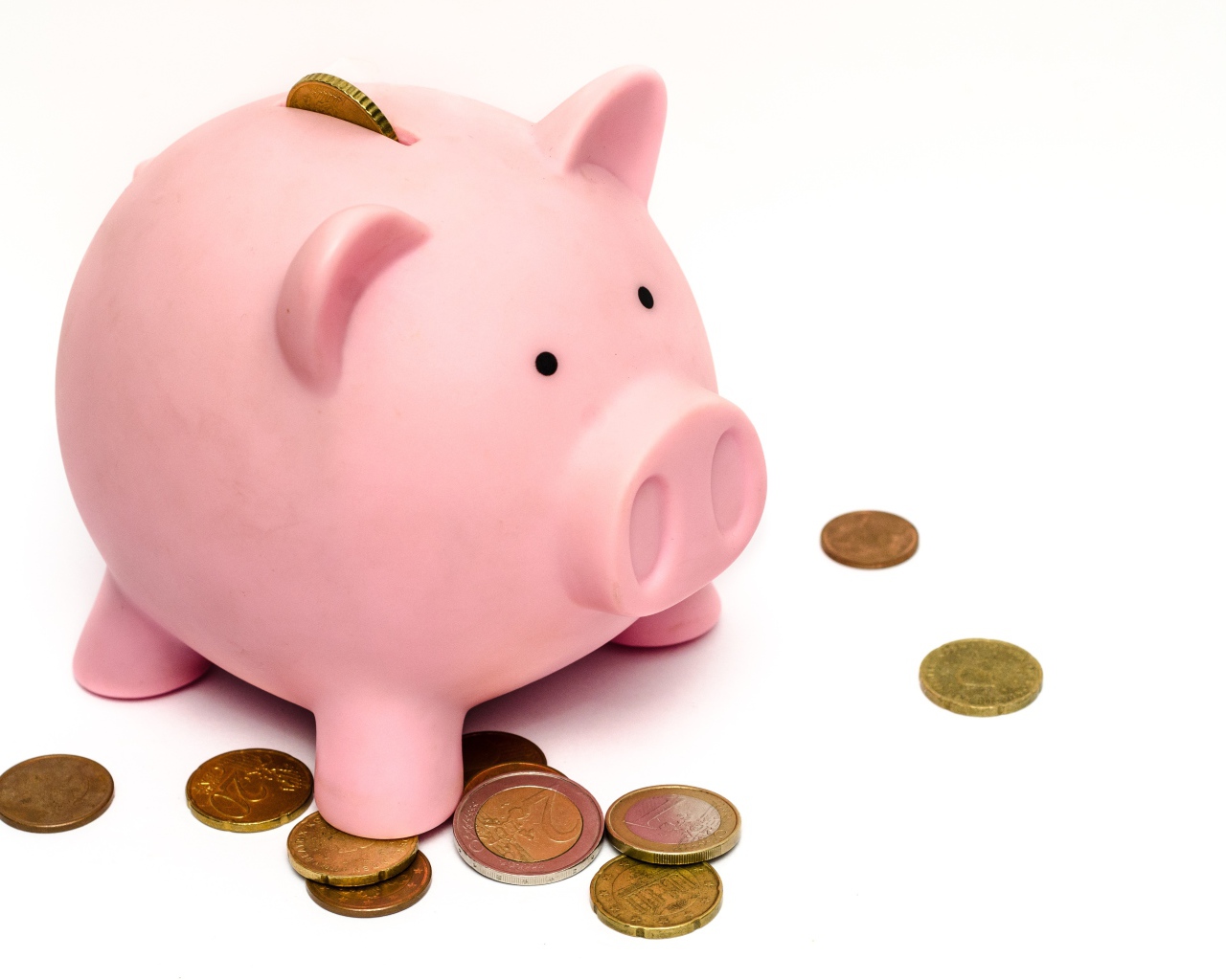 Розовая свинья копилка с монетами на белом фоне