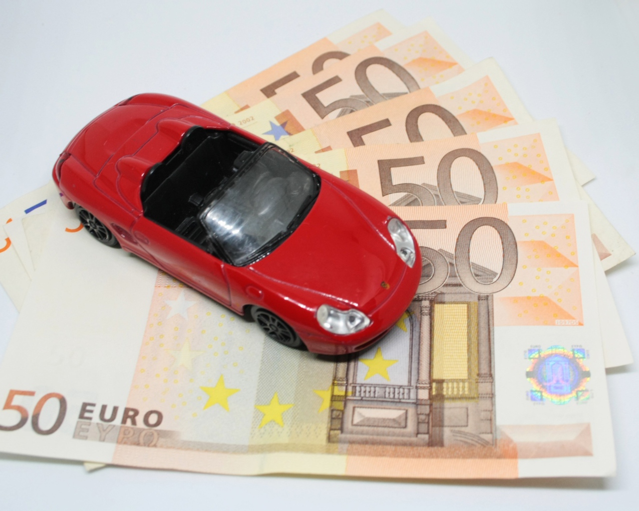 Красная игрушечная машинка с купюрами евро 
