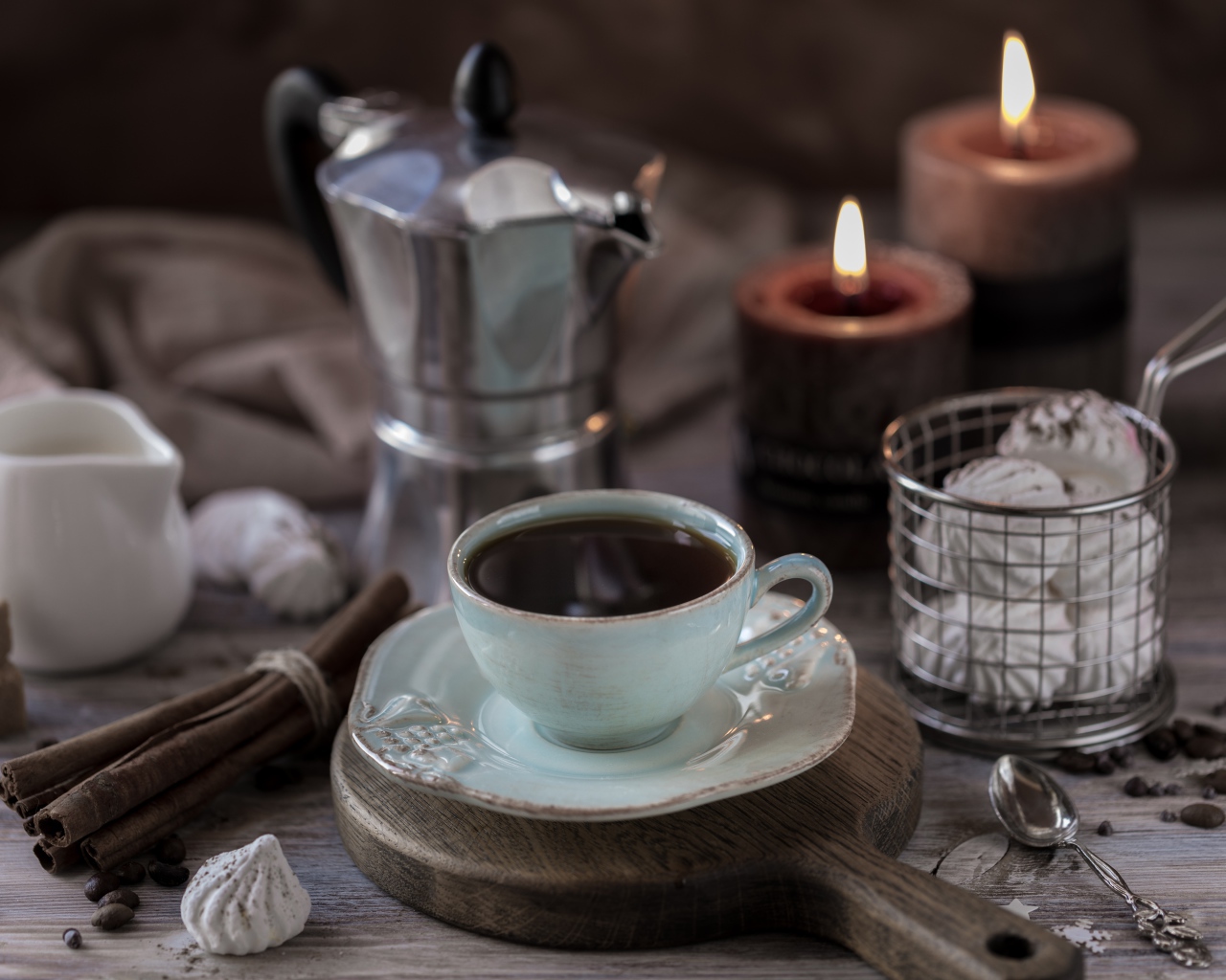 Чашка эспрессо на столе с корицей, зефиром и зажженными свечами