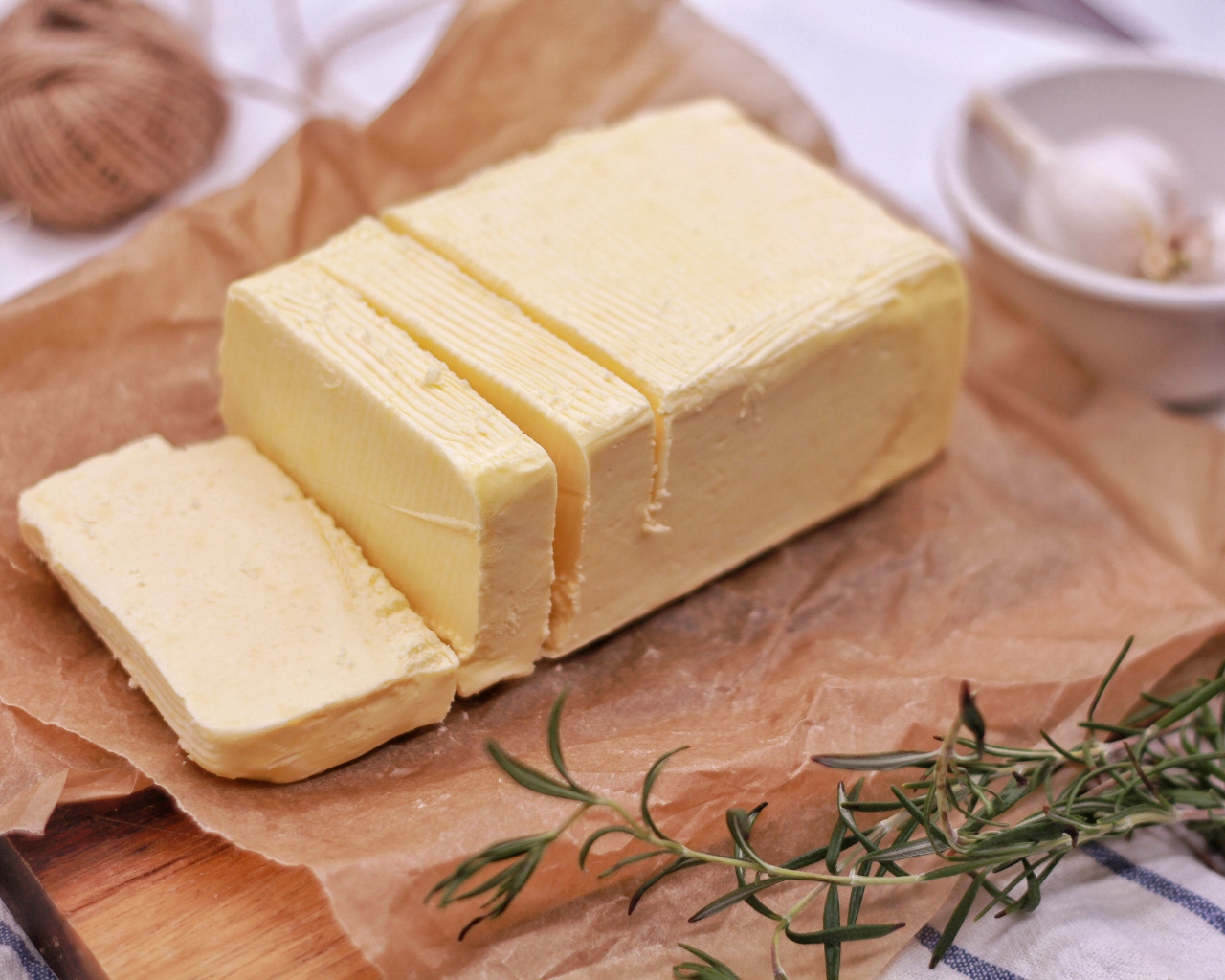 A piece of fresh butter on the table with rosemary and garlic