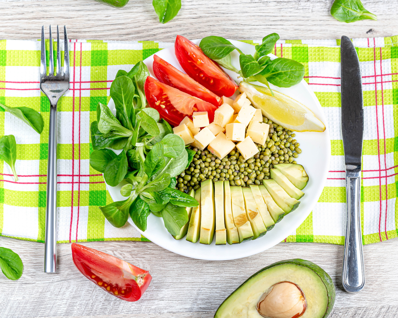 Аппетитные  свежие овощи с сыром и лимоном на тарелке 