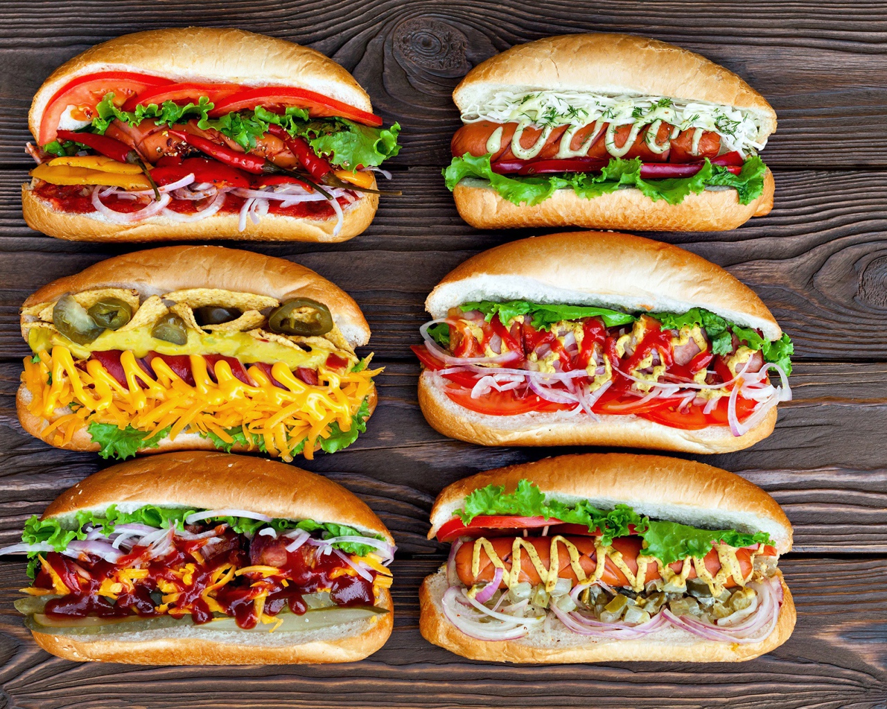 Аппетитные хот доги с разной начинкой на деревянном столе 