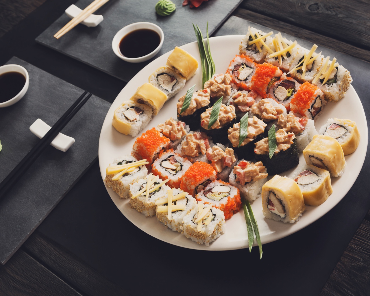 Аппетитные роллы на большой тарелке на столе с соусом