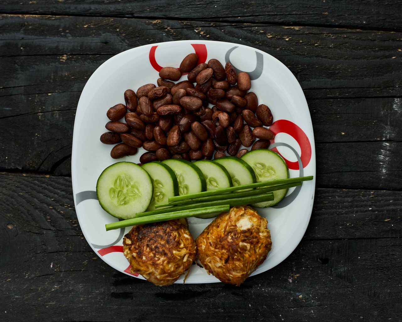 Фасоль на тарелке с оладьями и огурцами 