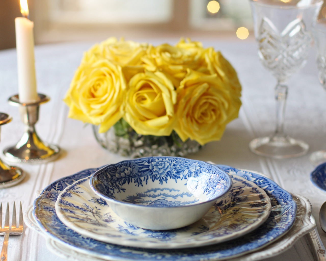 Красивая посуда на столе с букетом роз и свечами