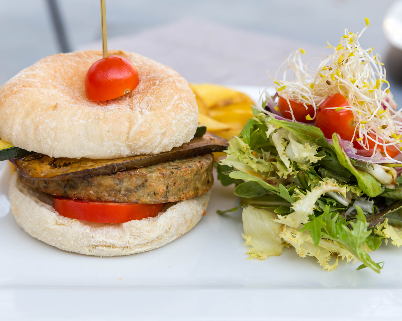 Большой гамбургер с салатом на столе 