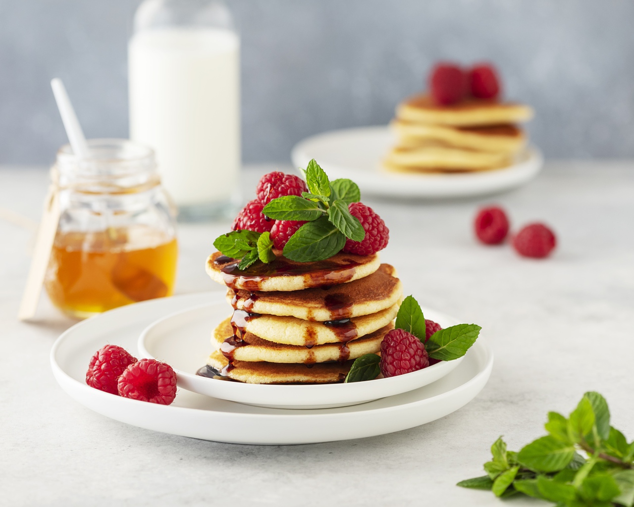 Румяные оладьи на тарелке с малиной и мятой 