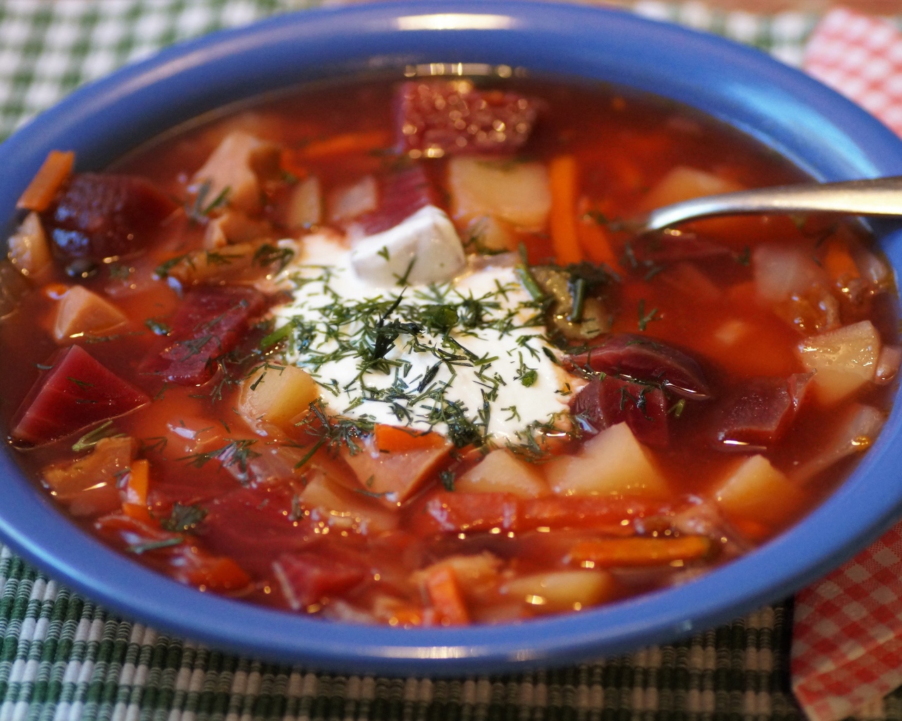 Борщ со сметаной в синей миске на столе 
