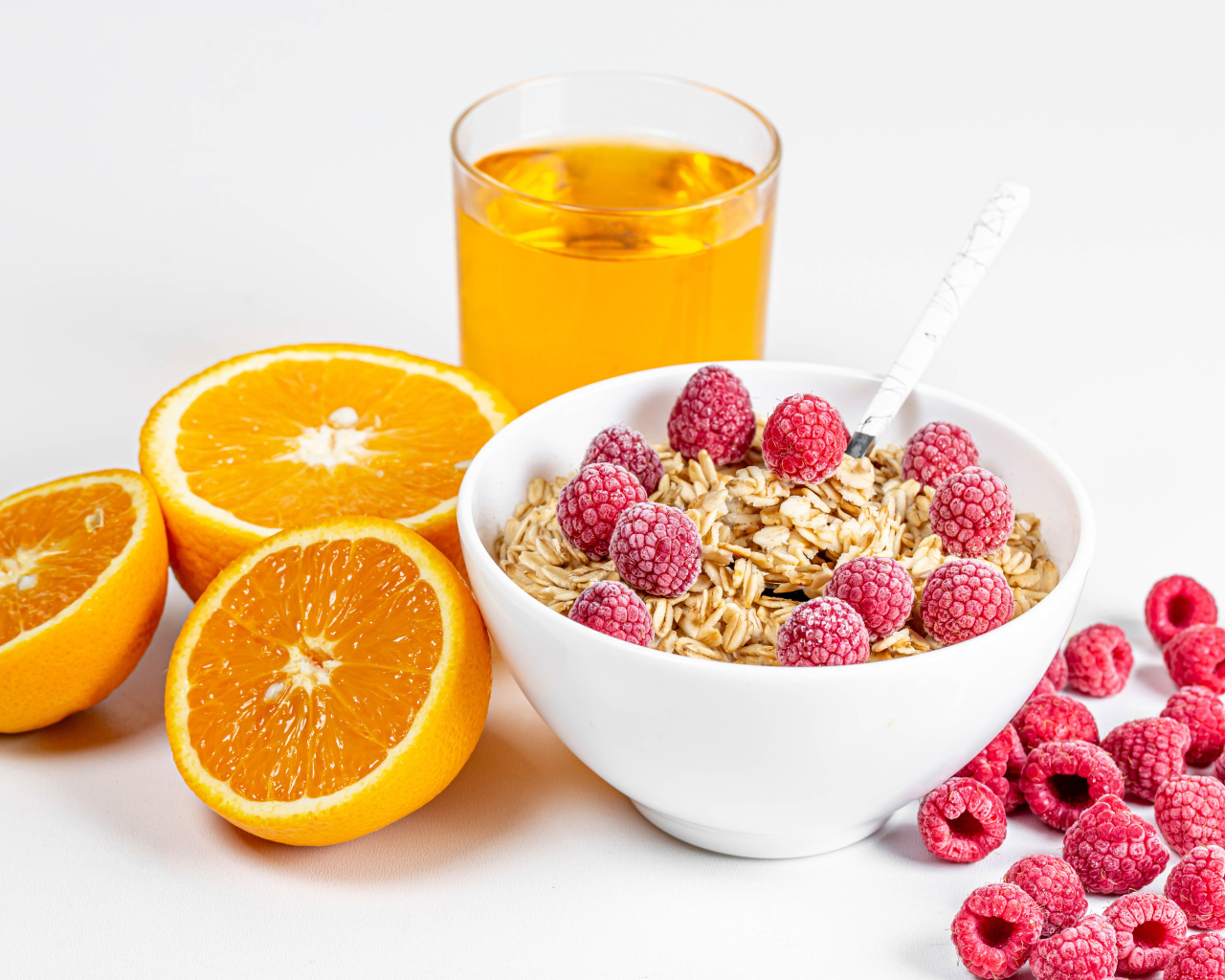 Миска мюсли с ягодами малины и апельсинами на столе с соком