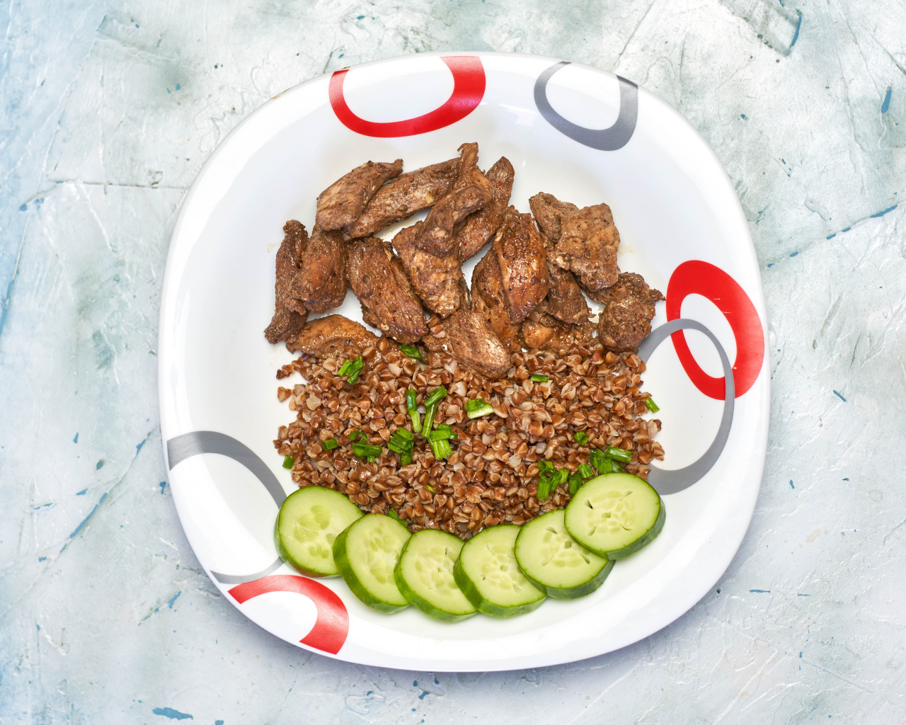 Гречка на тарелке с мясом и огурцами