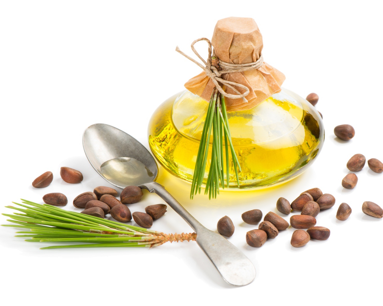 Кедровое масло на белом фоне с орехами и ложкой