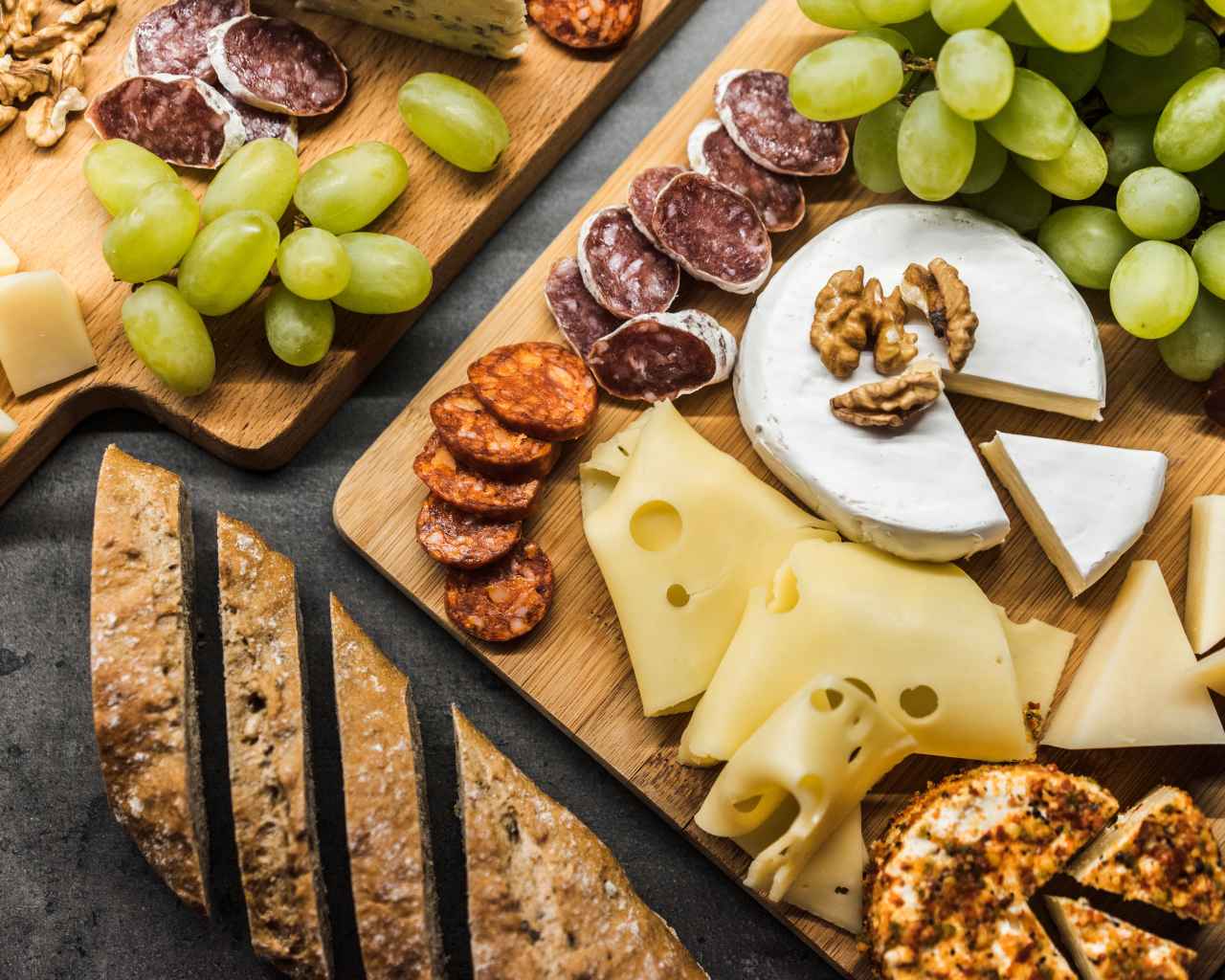 Сыр, колбаса, виноград и батон  на столе 