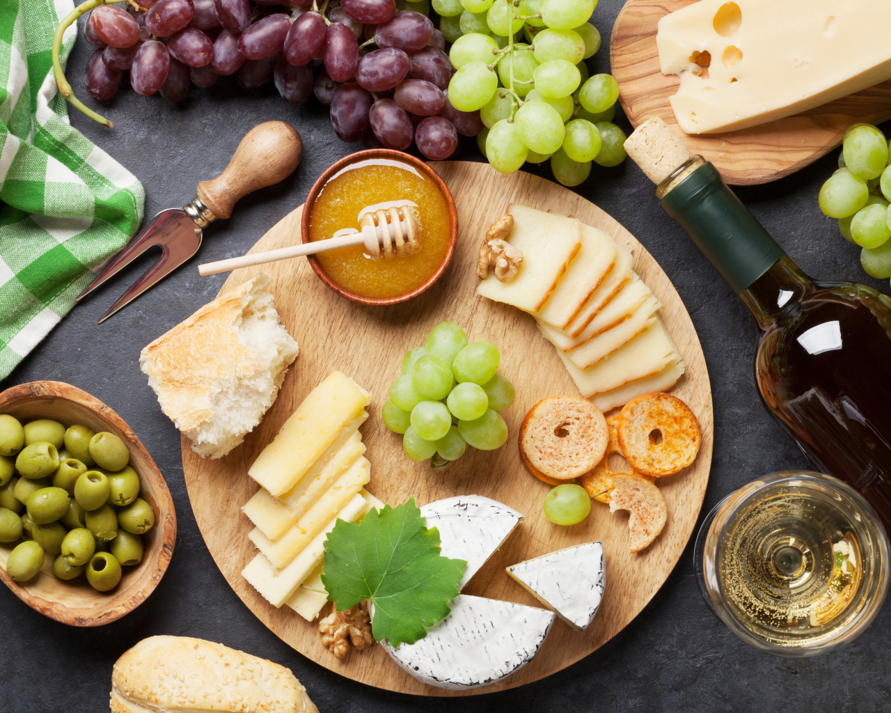 Сыр на столе с виноградом, оливками и белым вином