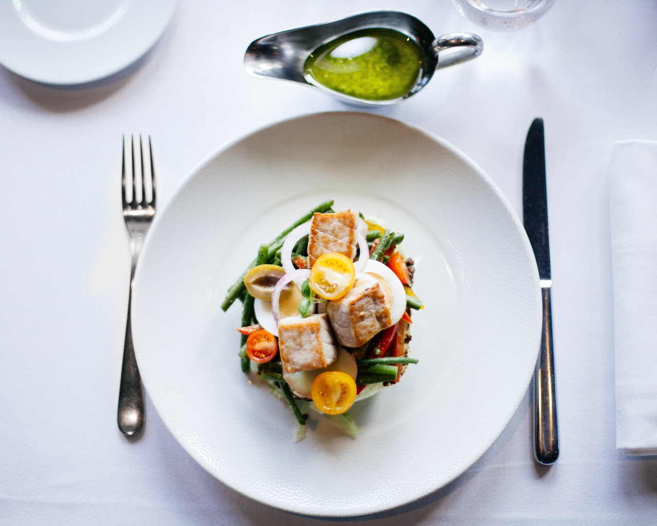 Салат из куриного филе с овощами на белой тарелке