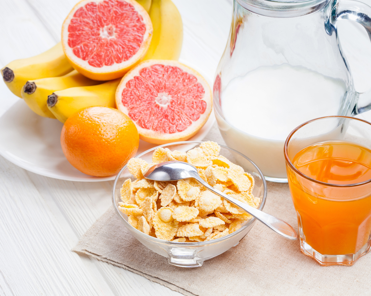 Кукурузные хлопья на столе с молоком, соком и свежими фруктами на завтрак