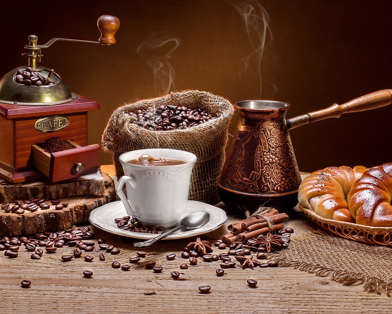 Чашка кофе на столе с круассанами и кофемолкой