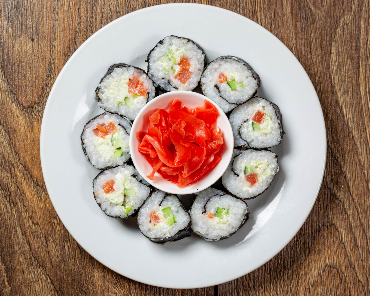 Вкусные суши на большой белой тарелке с имбирем