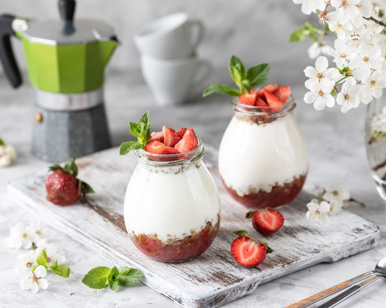 Десерт с йогуртом в банке с клубникой на столе цветами вишни 