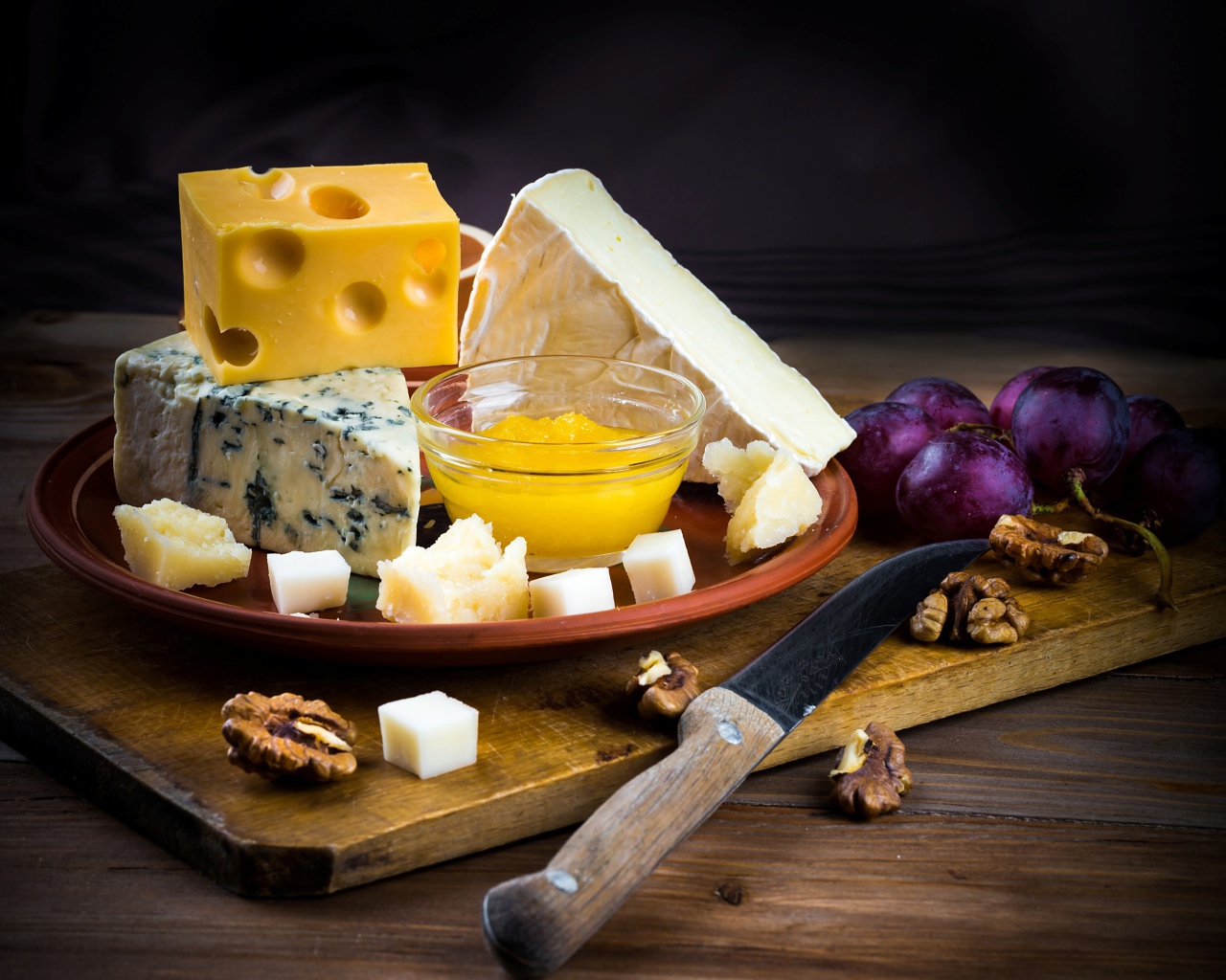 Разные виды сыра на столе с виноградом и орехами