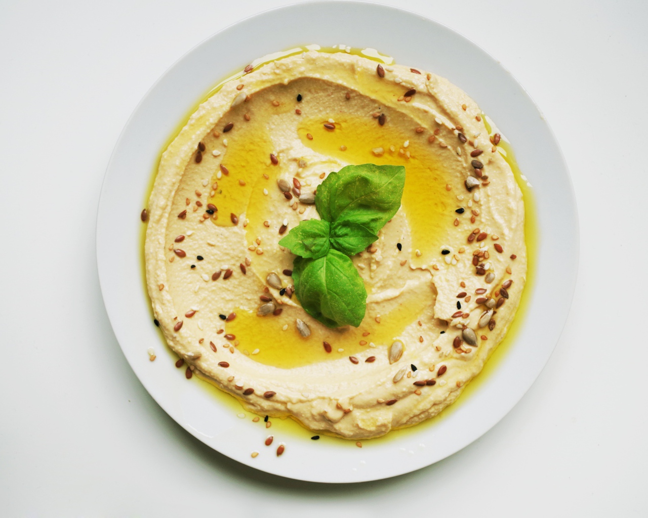 Блюдо хумус размазан по тарелке на сером фоне