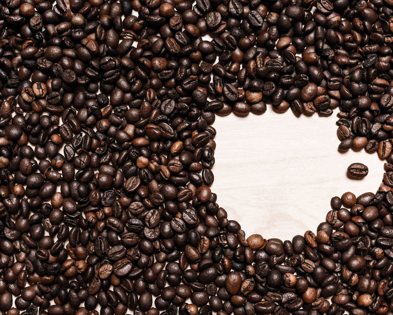 Рисунок чашки из кофейных зерен на столе