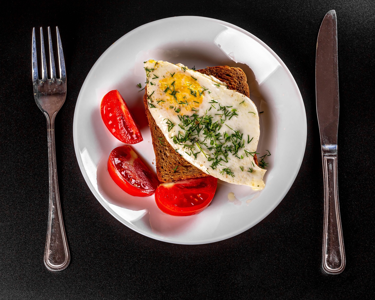 Бутерброд с яичницей на тарелке с помидорами