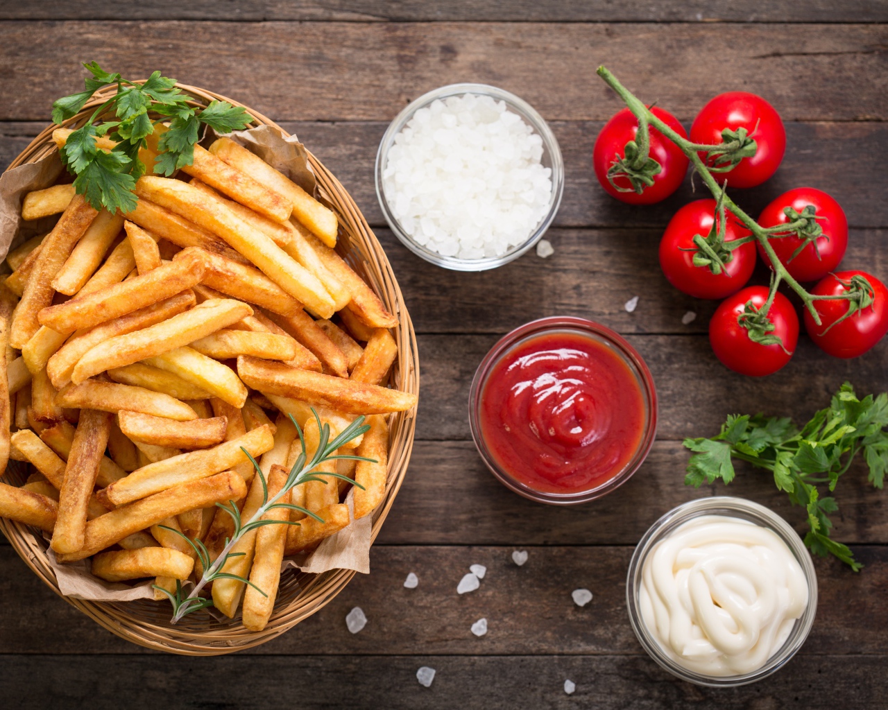 Картофель фри на столе соусом, солью и помидорами 