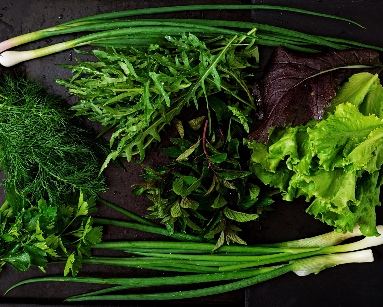 Свежая мокрая зелень лежит на столе 