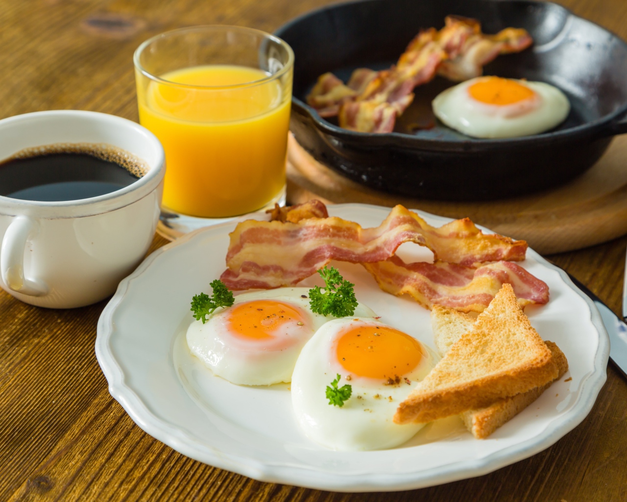 Яичница с беконом и тостами на столе с соком и кофе
