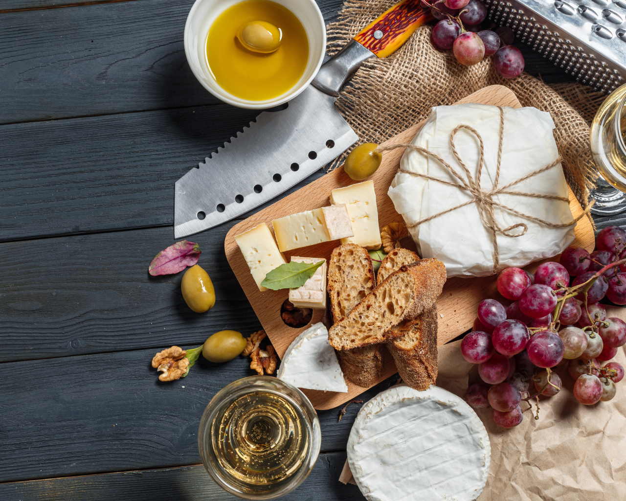 Grapes on a table with cheese, bread and olives