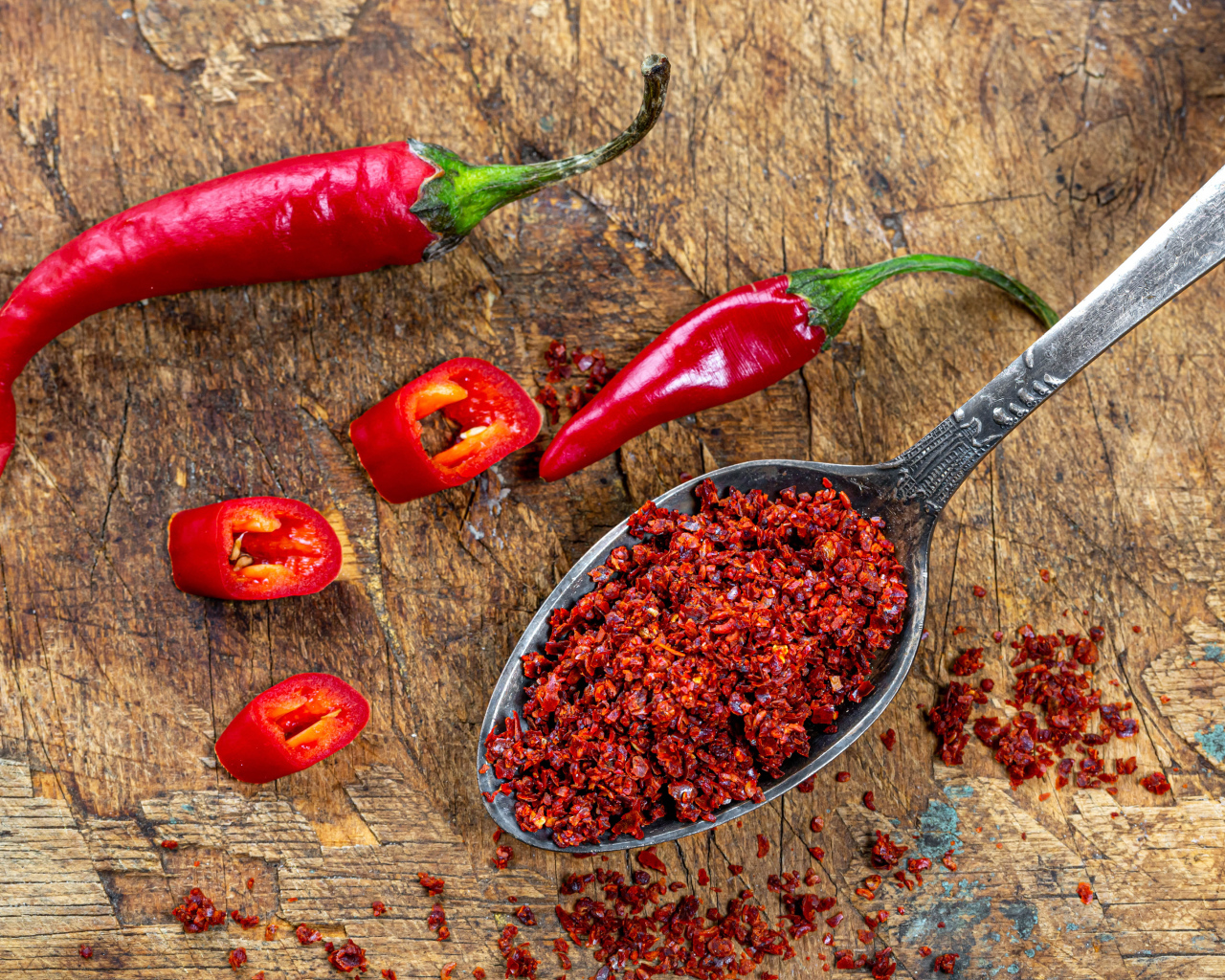 Молотый красный перец на ложке на столе 