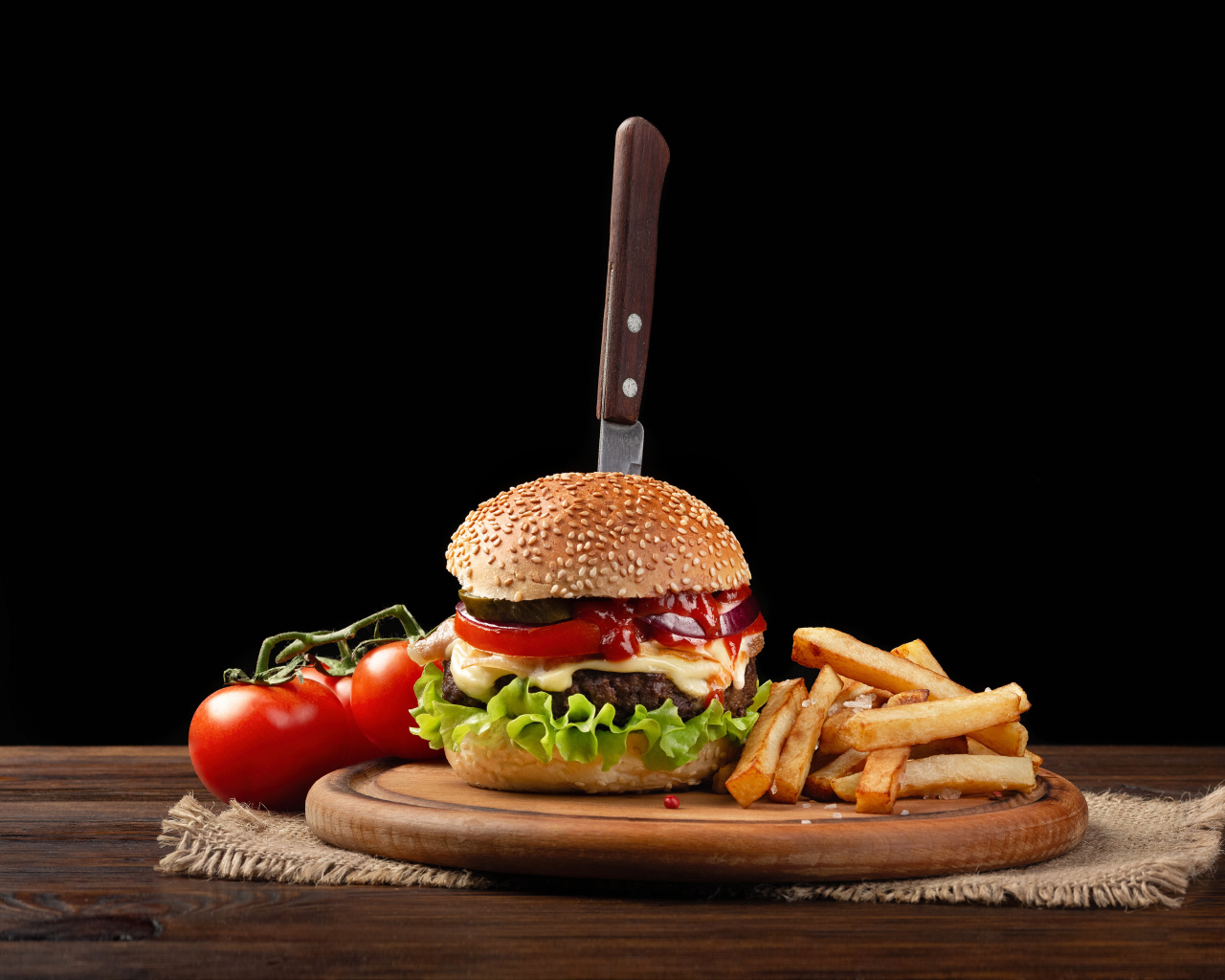 Гамбургер с ножом на столе с помидорами и картофелем фри 