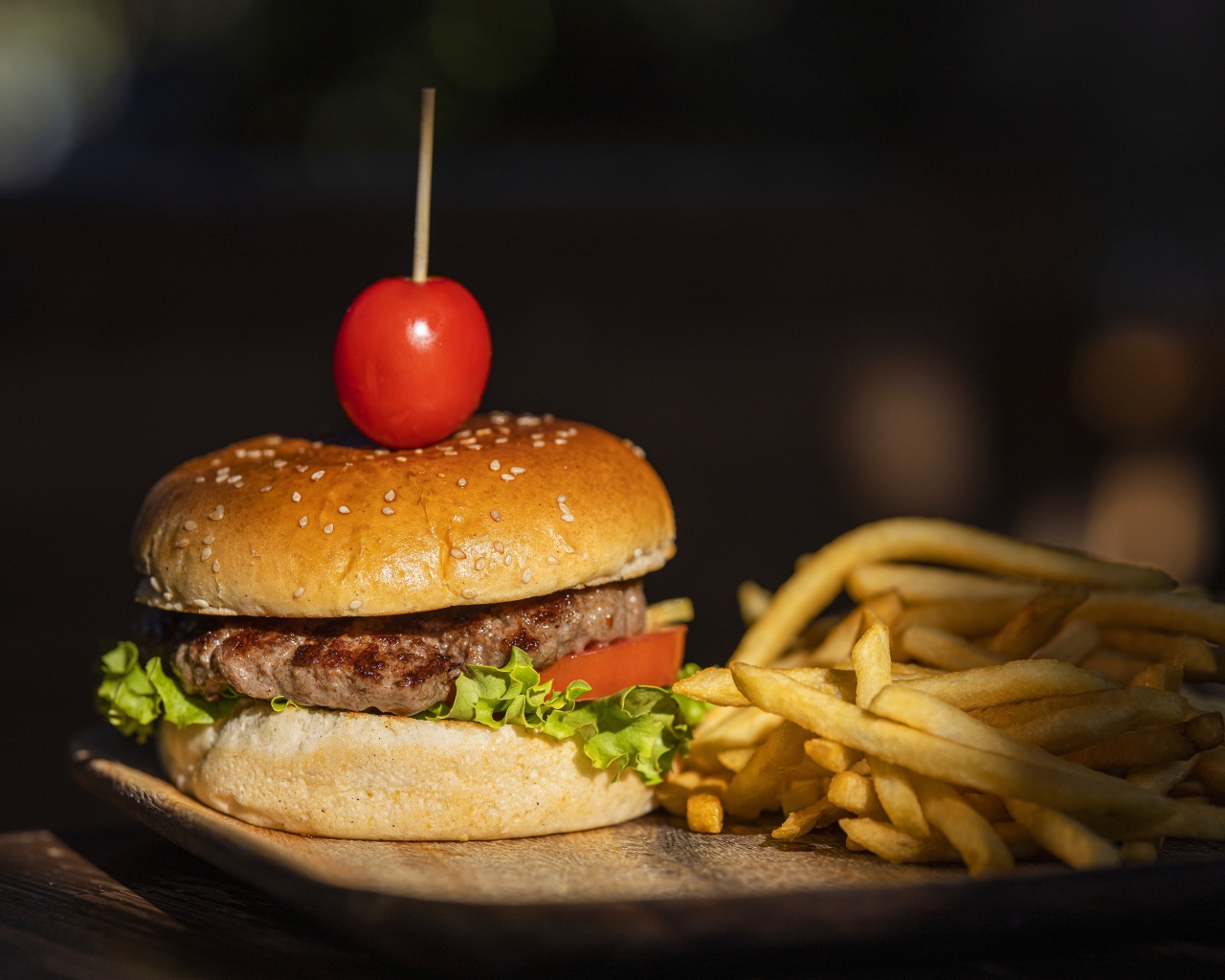Гамбургер с помидором на доске с картофелем фри 